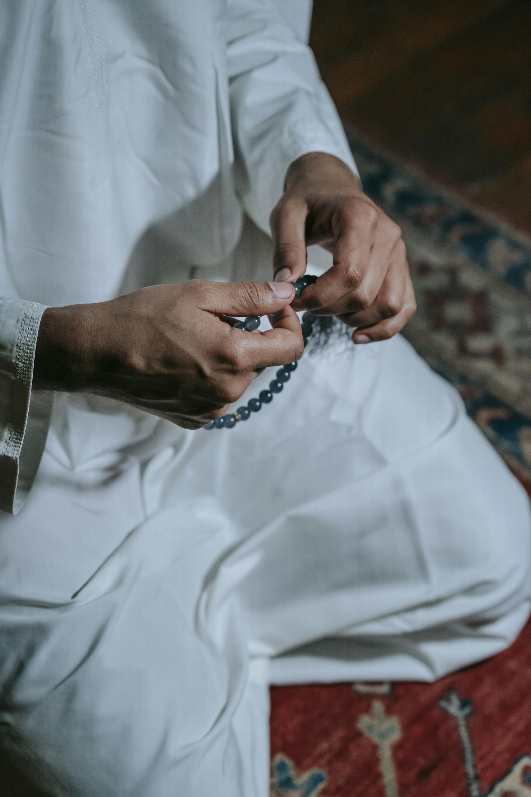 A man in traditional attire holding prayer beads, signifying faith and spirituality.